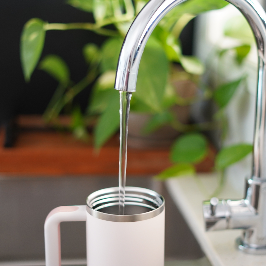 Stanley reusable water bottle filling up with tap water from kitchen tap
