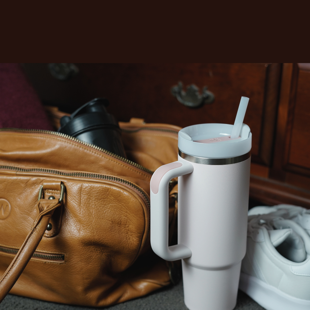 Stanley cup containing Access Filter Straw beside gym bag with shaker and towel and gym shoes