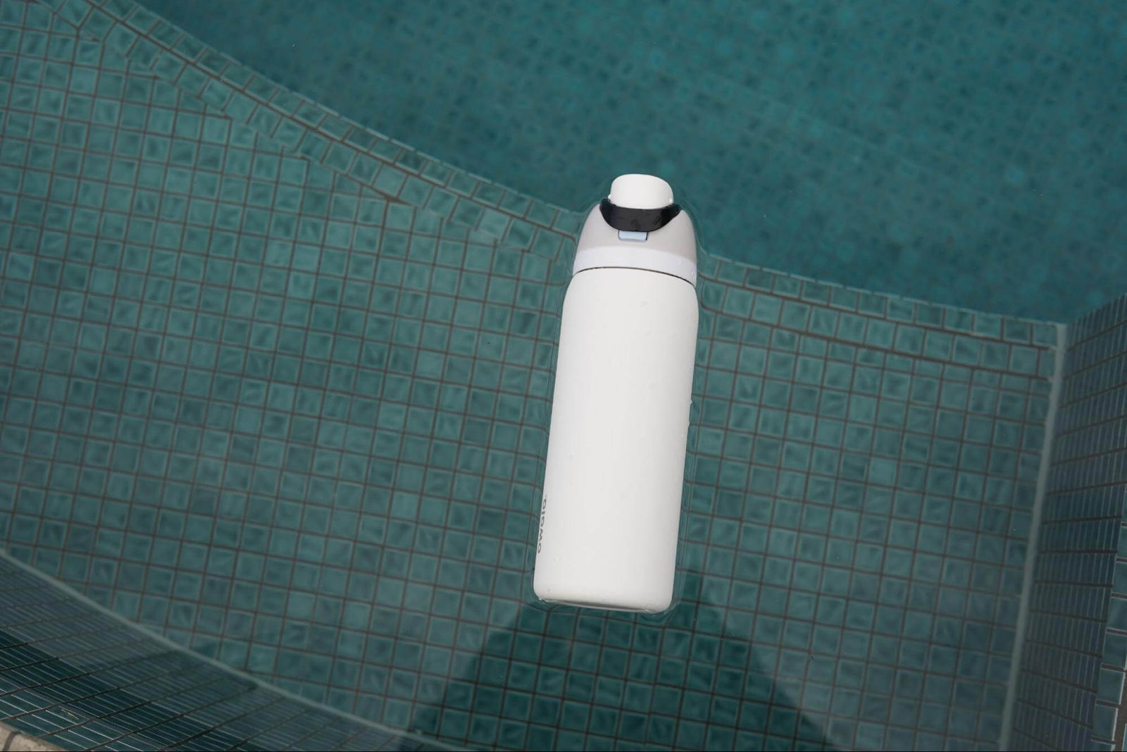 White Owala Reusable water bottle containing Access Filter Straw in pool